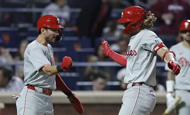 Philadelphia Phillies' Alec Bohm is congratulated by Trea Turner, left, after hitting a three-run home run during the fourth inning of a baseball game against the New York Mets, Friday, Sept. 20, 2024, in New York. (AP Photo/Adam Hunger)