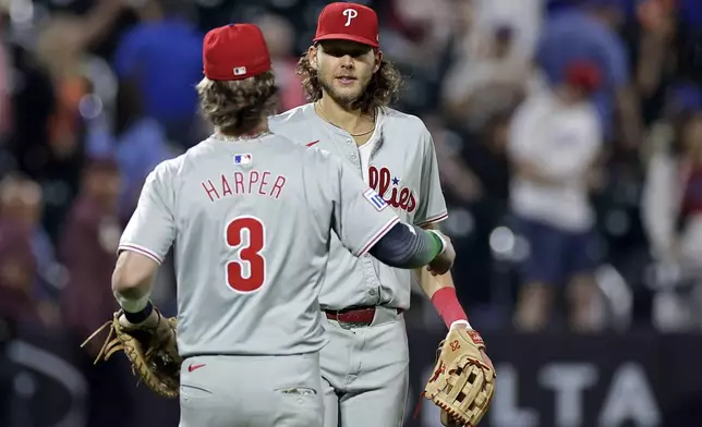 Philadelphia Phillies third baseman Alec Bohm, right, and Bryce Harper (3) celebrate after defeating the New York Mets in a baseball game Friday, Sept. 20, 2024, in New York. (AP Photo/Adam Hunger)