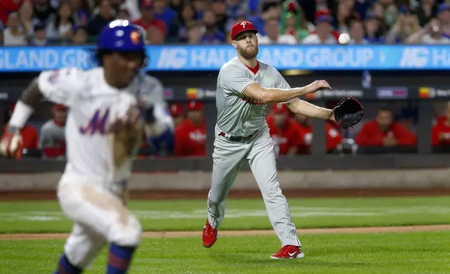 Philadelphia Phillies pitcher Zack Wheeler, right, throws to first to retire New York Mets batter Luisangel Acuna, left, during a baseball game Sunday, Sept. 22, 2024, in New York. (AP Photo/John Munson)