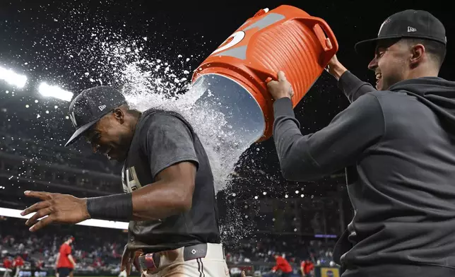 Washington Nationals' Stone Garrett, left, is doused by teammates after defeating the Philadelphia Phillies in a baseball game, Friday, Sept. 27, 2024, in Washington. (AP Photo/Terrance Williams)