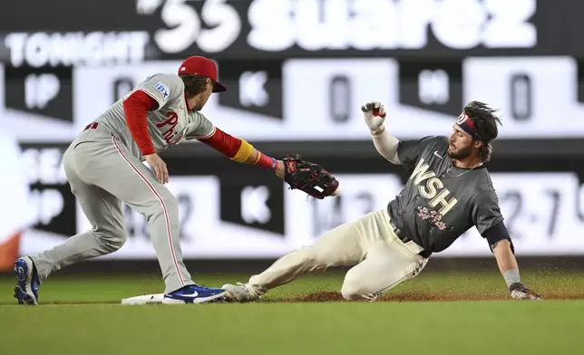 Washington Nationals' Dylan Crews slides into second base after hitting a double against Philadelphia Phillies pitcher Ranger Suárez and avoids the tag from second base Bryson Stott during the first inning of a baseball game, Friday, Sept. 27, 2024, in Washington. (AP Photo/Terrance Williams)