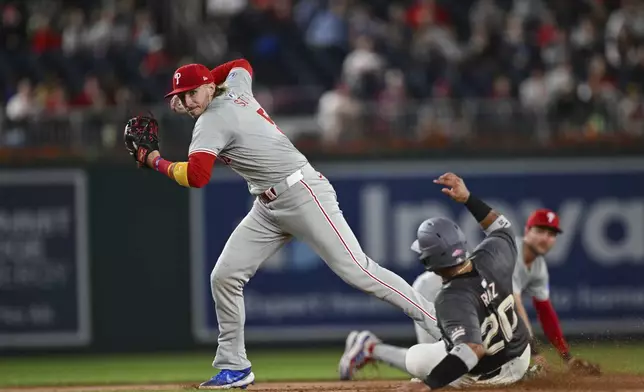 Philadelphia Phillies second baseman Bryson Stott attempts to turn a double play as Washington Nationals' Keibert Ruiz slides into second base on a ball hit by Stone Garrett during the second inning of a baseball game, Friday, Sept. 27, 2024, in Washington. (AP Photo/Terrance Williams)