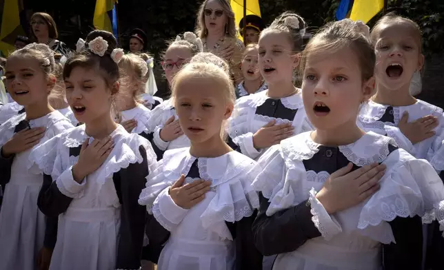 Schoolgirls sing the national anthem on the first day at school in a cadet lyceum in Kyiv, Ukraine, Monday, Sept. 2, 2024. Children and students went to school despite the fact that Kyiv was hit by massive Russian missile barrage early in the morning, causing fires, damaged buildings and infrastructure objects. (AP Photo/Efrem Lukatsky)