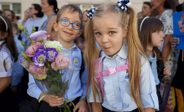 Astryd and Adam, 6 and a half years-old, strike a pose during a ceremony marking the beginning of the school year at the Orizont Elementary School in Bucharest, Romania, Monday, Sept. 9, 2024. (AP Photo/Vadim Ghirda)