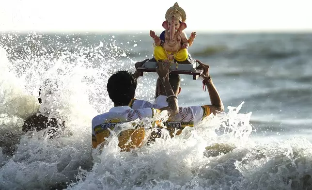 Devotees immerse an idol of elephant-headed Hindu god Ganesha in the Arabian Sea, during the ten days long Ganesh Chaturthi festival in Mumbai, India, Sunday, Sept. 8, 2024. (AP Photo/Rafiq Maqbool)