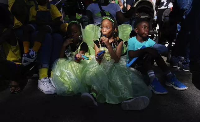 Naailah Reese, 4, left, Nayyara Reese, 8, center, and Kade Lewis, 8, right, all of Atlanta, watch the parade during Dragon Con on Saturday, Aug. 31, 2024, in Atlanta. (AP Photo/Brynn Anderson)