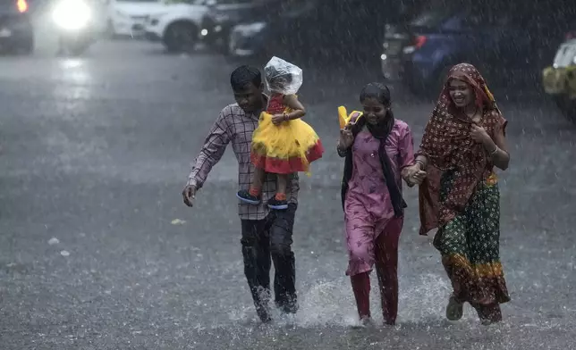 A family run as they cross a street during heavy rain in Hyderabad, India, Friday, Sept. 6, 2024. (AP Photo/Mahesh Kumar A.)