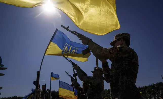 Honor guards shoot into the air during the funeral ceremony of six Ukrainian servicemen killed in a Russian rocket attack at a Ukrainian military academy, during their funeral ceremony in Poltava, Ukraine, Saturday Sept. 7, 2024. (AP Photo/Evgeniy Maloletka)