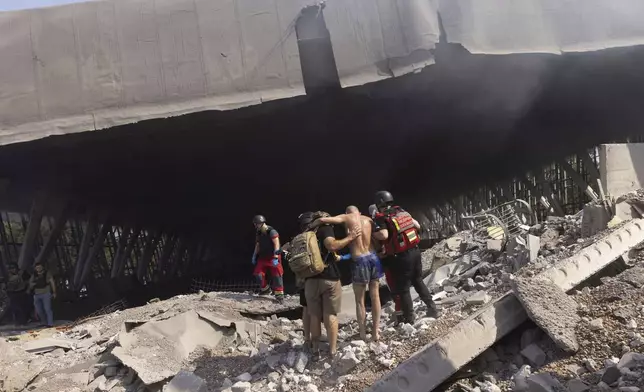 Paramedics help an injured man to walk out of the rubble at a sports facility destroyed after a Russian attack in Kharkiv, Ukraine, Sunday, Sept. 1 2024. (AP Photo/Yevhen Titov)