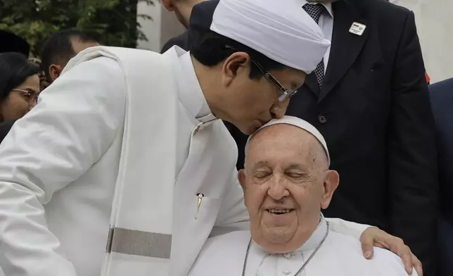 The Grand Imam of Istiqlal Mosque Nasaruddin Umar, left, hugs Pope Francis during a family photo following an interreligious meeting with religious leaders at the Istiqlal Mosque in Jakarta, Thursday, Sept. 5, 2024. (Yasuyoshi Chiba/Pool Photo via AP)