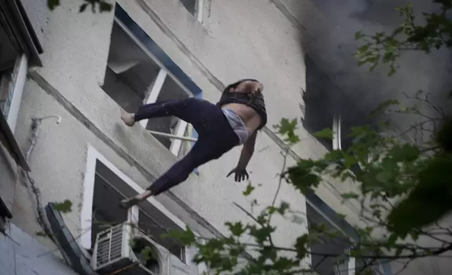 A man falls down to death from a burning apartment window after Russia's guided air bomb strike in Kharkiv, Ukraine, Friday, Aug. 30, 2024. Russian attack on the northeastern city of Kharkiv using powerful plane-launched glide bombs killed five people, including a 14-year-old girl on a playground, and wounded 47 others, regional Gov. Oleh Syniehubov said. (AP Photo/Andrii Marienko)