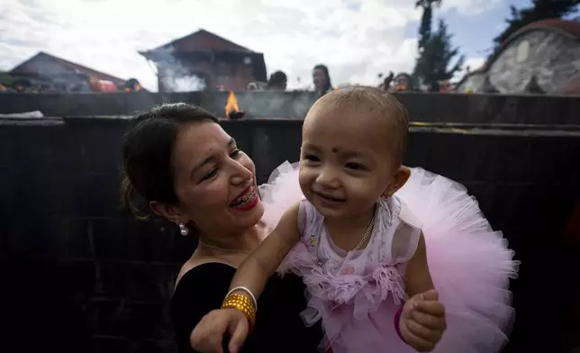 A woman plays with her child at the Pashupatinath temple during Teej festival celebrations in Kathmandu, Nepal, Friday, Sept. 6, 2024. (AP Photo/Niranjan Shrestha)