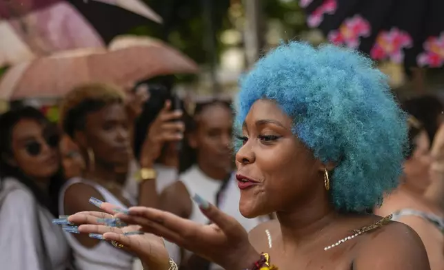 A woman with blue hair blows a kiss to the audience as she walks the runway at a fashion show of Afro hairstyles in Havana, Cuba, Saturday, Aug. 31, 2024. (AP Photo/Ramon Espinosa)