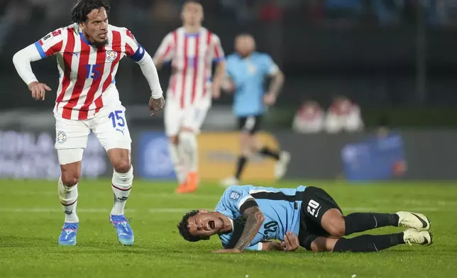 Uruguay's Maximiliano Araujo, right, falls on the pitch after being fouled by Paraguay's Gustavo Gomez during a qualifying soccer match for the FIFA World Cup 2026, in Montevideo, Uruguay, Friday, Sept. 6, 2024. (AP Photo/Matilde Campodonico)