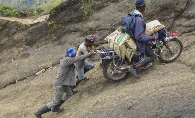 People help a motorcycle driver up a mountain to avoid gang violence in the Kenscoff neighborhood of Port-au-Prince, Haiti, Tuesday, Sept. 10, 2024. (AP Photo/Odelyn Joseph)