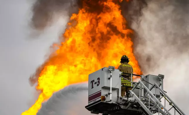 A firefighter directs a line of water around a fire on a pipeline carrying liquified natural gas near Spencer Highway and Summerton on Monday, Sept. 16, 2024, in La Porte, Texas. (Brett Coomer/Houston Chronicle via AP)