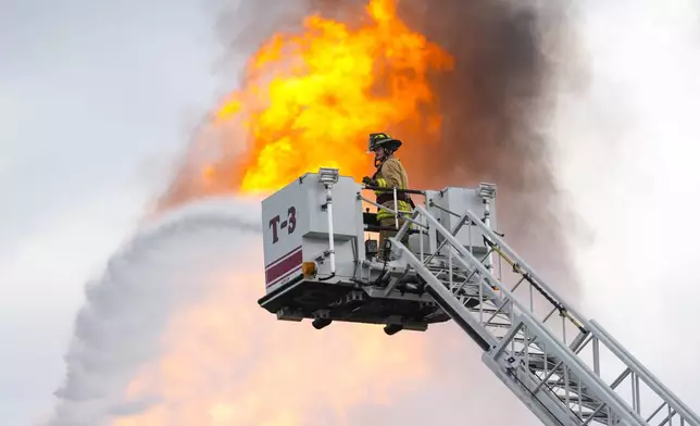 A firefighter directs a line of water around a fire on a pipeline carrying liquified natural gas near Spencer Highway and Summerton on Monday, Sept. 16, 2024, in La Porte, Texas. (Brett Coomer/Houston Chronicle via AP)