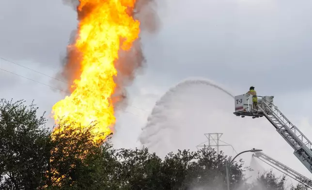 A firefighter directs a line of water around a fire on a pipeline carrying liquified natural gas near Spencer Highway and Summerton on Monday, Sept. 16, 2024, in La Porte, Texas. (Brett Coomer/Houston Chronicle via AP)