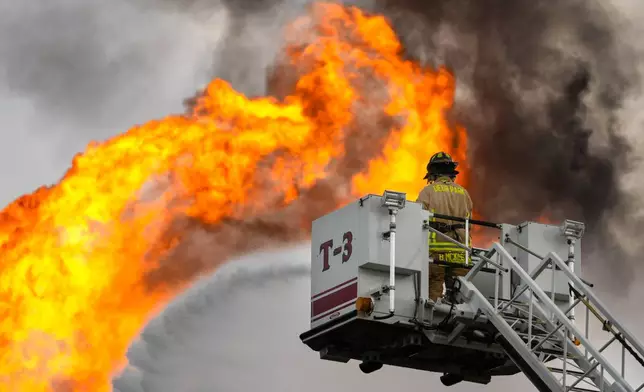 A firefighter directs a line of water around a fire on a pipeline carrying liquified natural gas near Spencer Highway and Summerton on Monday, Sept. 16, 2024, in La Porte, Texas. (Brett Coomer/Houston Chronicle via AP)