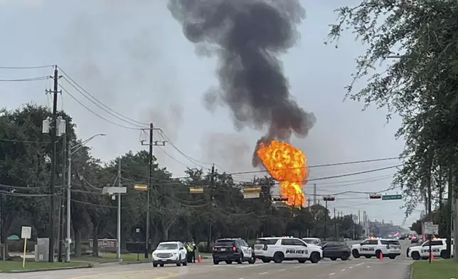 Police block off a highway as a large fire from a pipeline explosion burns near La Porte, Texas, on Monday, Sept. 16, 2024. (AP Photo/Lekan Oyekanmi)