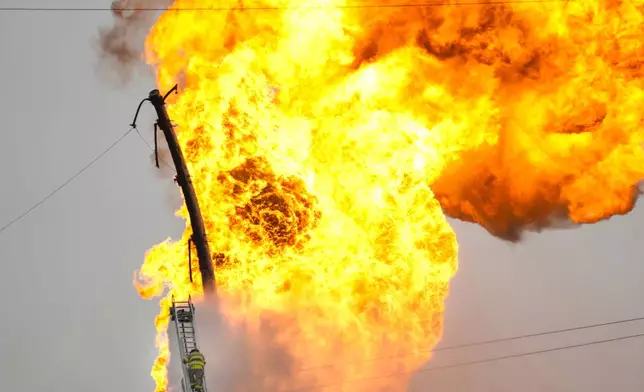 A firefighter directs a line of water around a fire on a pipeline carrying liquified natural gas near Spencer Highway and Summerton on Monday, Sept. 16, 2024, in La Porte, Texas. (Brett Coomer/Houston Chronicle via AP)