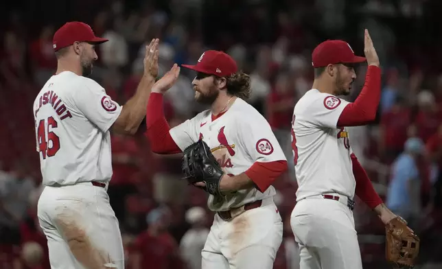 St. Louis Cardinals' Paul Goldschmidt, left, Brendan Donovan, center, and Nolan Arenado, right, celebrate a 3-1 victory following a baseball game against the Pittsburgh Pirates Tuesday, Sept. 17, 2024, in St. Louis. (AP Photo/Jeff Roberson)