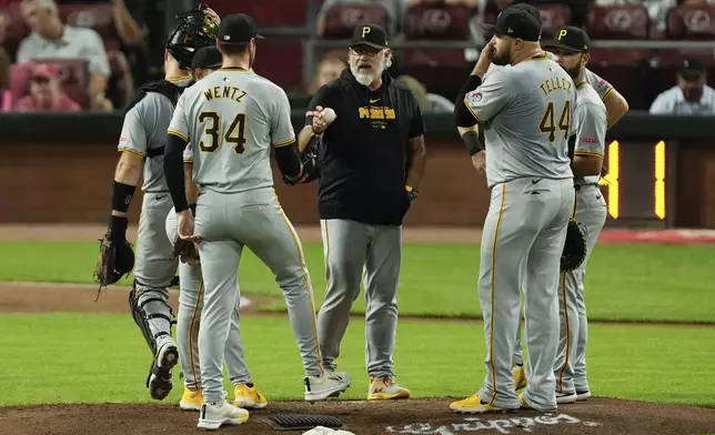 Pittsburgh Pirates manager Derek Shelton, center, hands the ball to pitcher Joey Wentz (34) during a pitching change in the fourth inning of a baseball against the Cincinnati Reds, Friday, Sept. 20, 2024, in Cincinnati. (AP Photo/Carolyn Kaster)