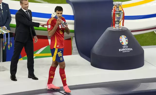 FILE - Spain's Rodri holds the player of the tournament trophy after the final match between Spain and England at the Euro 2024 soccer tournament in Berlin, Germany, July 14, 2024. Jude Bellingham and Rodri have key starring roles for title-winning soccer clubs and their national teams. Neither is currently playing matches. (AP Photo/Andreea Alexandru, File)