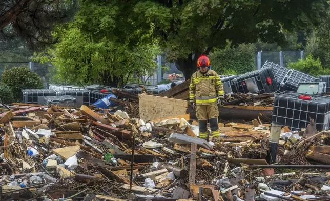 This handout photo provided by the Polish fire department, shows firefighters removing piles of debris dumped in the streets by high flood wave that is passing through southwestern Poland, in Glucholazy, Poland, on Tuesday, Sept. 17, 2024. ( Marcin Muskala/KG PSP via AP)