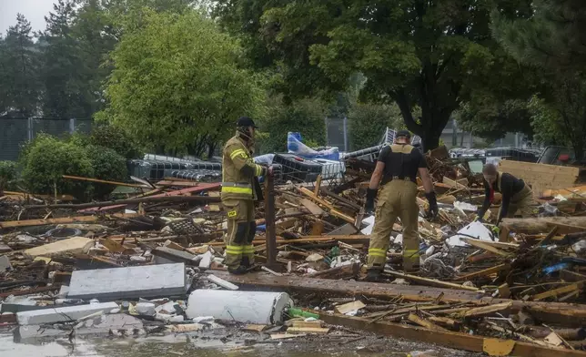 This handout photo provided by the Polish fire department, shows firefighters removing piles of debris dumped in the streets by high flood wave that is passing through southwestern Poland, in Glucholazy, Poland, on Tuesday, Sept. 17, 2024. ( Marcin Muskala/KG PSP via AP)