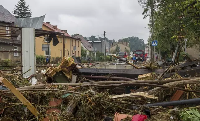 This handout photo provided by the Polish fire department, shows firefighters removing piles of debris dumped in the streets by high flood wave that is passing through southwestern Poland, in Glucholazy, Poland, on Tuesday, Sept. 17, 2024. ( Marcin Muskala/KG PSP via AP)