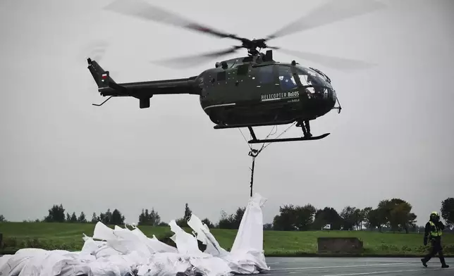 On this handout photo provided by the State Fire Service of Poland, a police helicopter carries sandbags to strengthen the Nysa Klodzka River's embankments against the flood wave in the town of Nysa, southwestern Poland, Tuesday, Sept.17, 2024. Authorities said the town has avoided major flooding, unlike many other locations in the region. (Maciej Krysinski/KG PSP via AP)