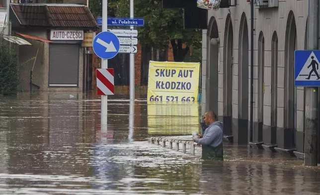 A man stands in waist-deep water that has flooded the streets and houses in the town of Kłodzko, in Poland's southwest, Sunday, Sept. 15, 2024, after days of unusually heavy rain. (AP Photo/Krzysztof Zatycki)