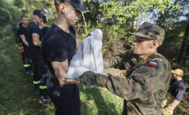 Soldiers fill and arrange sandbags to help strengthen the embankments and to prevent flooding near the city of Wroclaw, southwestern Poland, Tuesday, Sept. 17, 2024. (AP Photo/Krzysztof Zatycki)