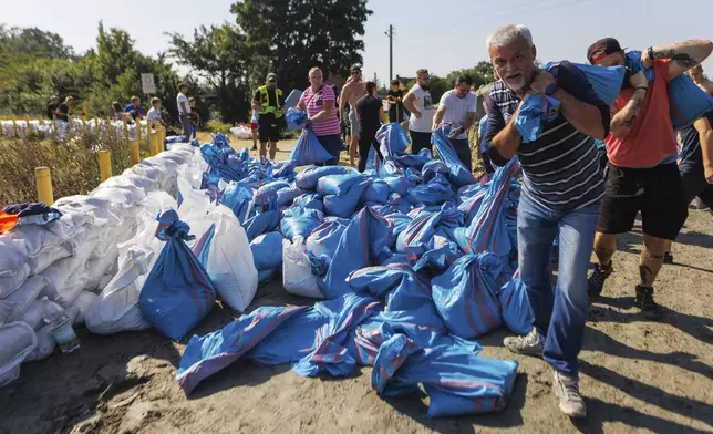 Residents use sandbags to strengthen the embankment of the Oder River on its way to Wroclaw, southwestern Poland, Tuesday, Sept. 17, 2024. (AP Photo/Krzysztof Zatycki)