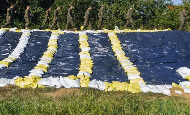 Soldiers who help strengthen the embankments and to prevent floodings walk by sandbags near the city of Wroclaw, southwestern Poland, Tuesday, Sept. 17, 2024. (AP Photo/Krzysztof Zatycki)