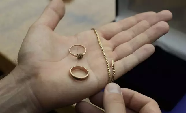 A relative shows golden jewelry that was confiscated by Nazi Germans from Zofia Strusińska and her sister Józefa Skórka, who were captured by Nazi troops during Warsaw Uprising in 1944 and taken to a forced labor camp. Their seized items that had been stored at Germany's Arolsen Archives, were returned to their relatives in a ceremony in Warsaw, Poland, on Tuesday, Sept. 10, 2024, in which 10 other families also had belongings of their relatives returned. (AP Photo/Czarek Sokolowski)