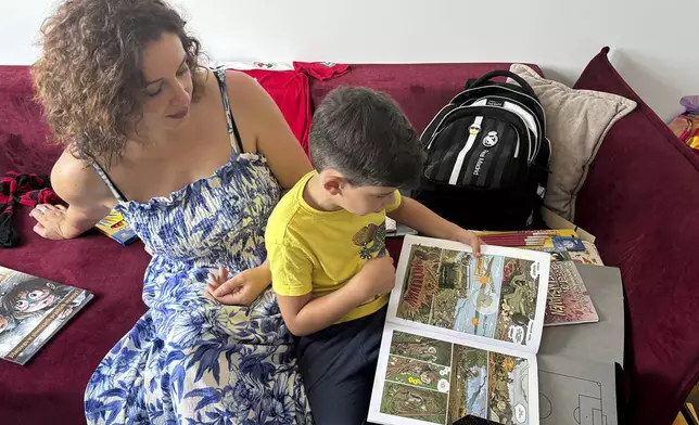 Sava Trypolsky, a 7-year-old boy from Ukraine, looks at his favorite comic book, which depicts World War II in Poland, with his mother Oksana Trypolska, in his room in Jablonna, Poland, Friday, Aug. 30, 2024. (AP Photo/Vanessa Gera)