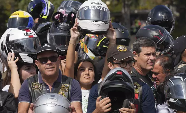 Faithful hold up their helmets to be blessed during the IX Pilgrimage of the Blessing of Helmets that draws tens of thousands at the Roman Catholic holy shrine of Fatima, in Fatima, Portugal, Sunday, Sept. 22, 2024. (AP Photo/Ana Brigida)