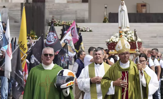 A priest carrying a Portuguese National Republican Guard motorcyclist helmet walks ahead of the Our Lady of Fatima statue in a procession closing the IX Pilgrimage of the Blessing of Helmets at the Roman Catholic holy shrine of Fatima to attend, in Fatima, Portugal, Sunday, Sept. 22, 2024. (AP Photo/Ana Brigida)