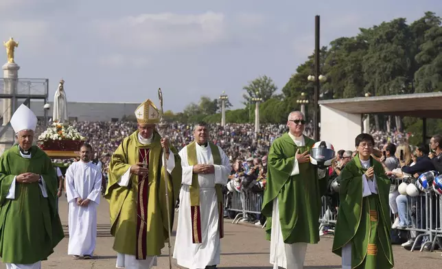 A priest carrying a Portuguese National Republican Guard motorcyclist helmet walks ahead of the Our Lady of Fatima statue in a procession starting the IX Pilgrimage of the Blessing of Helmets at the Roman Catholic holy shrine of Fatima to attend, in Fatima, Portugal, Sunday, Sept. 22, 2024. (AP Photo/Ana Brigida)