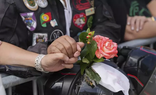 A couple hold hands while attending the IX Pilgrimage of the Blessing of Helmets that draws tens of thousands at the Roman Catholic holy shrine of Fatima, in Fatima, Portugal, Sunday, Sept. 22, 2024. (AP Photo/Ana Brigida)