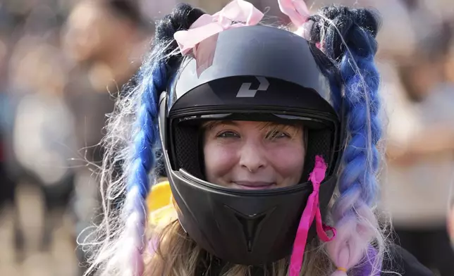 A woman wearing a decorated helmet arrives at the Roman Catholic holy shrine of Fatima to attend the IX Pilgrimage of the Blessing of Helmets that draws tens of thousands, in Fatima, Portugal, Sunday, Sept. 22, 2024. (AP Photo/Ana Brigida)