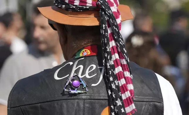 A man wearing a pin with rifles on his vest and the Stars and Stripes on his hat walks at the Roman Catholic holy shrine of Fatima during the IX Pilgrimage of the Blessing of Helmets that draws tens of thousands, in Fatima, Portugal, Sunday, Sept. 22, 2024. (AP Photo/Ana Brigida)