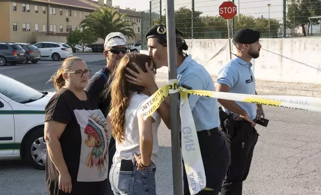 A police officer kisses a girl outside a school following a stabbing attack in Azambuja near Lisbon, Tuesday, Sept. 17, 2024. (AP Photo/Ana Brigida)