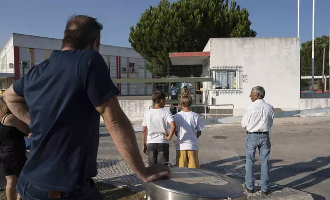 People stand outside a school following a stabbing attack in Azambuja near Lisbon, Tuesday, Sept. 17, 2024. (AP Photo/Ana Brigida)