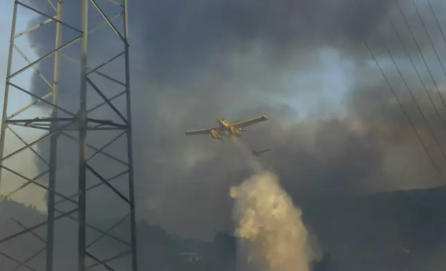 Firefighting airplanes drop water on a fire burning in Sever do Vouga, a town in northern Portugal that has been surrounded by forest fires, Monday, Sept. 16, 2024. (AP Photo/Bruno Fonseca)