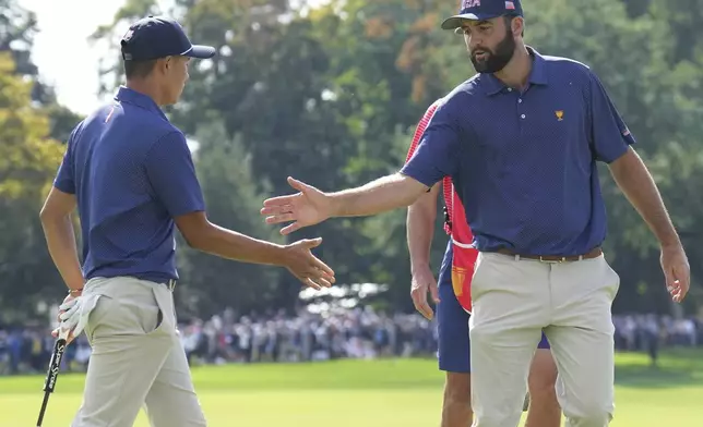 United States team member Scottie Scheffler, right, shakes hands with partner Collin Morikawa after making a putt on the 15th hole during the third round at the Presidents Cup golf tournament at Royal Montreal Golf Club in Montreal Saturday, Sept. 28, 2024. (Nathan Denette/The Canadian Press via AP)