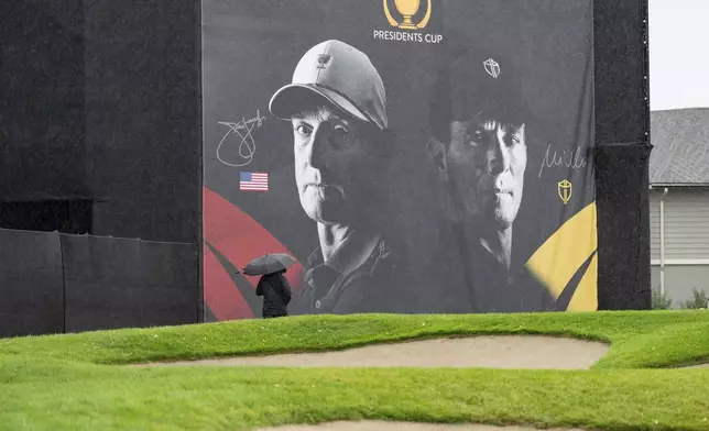 A man walks past a sign for the Presidents Cup golf tournament at the Royal Montreal Golf Club, Monday, Sept. 23, 2024 in Montreal. (Christinne Muschi/The Canadian Press via AP)