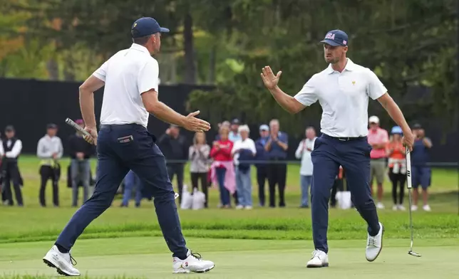 United States team members Keegan Bradley, left, and Wyndham Clark, right, react after Bradley sank a long putt on the 13th green during a first-round four-ball match at the Presidents Cup golf tournament at the Royal Montreal Golf Club in Montreal, Thursday, Sept. 26, 2024. (Nathan Denette/The Canadian Press via AP)